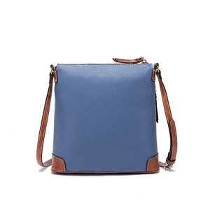 Detail of dark blue pebble leather crossbody bag with brown trim and stitching