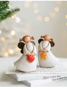 Detail of handcrafted resin angels holding a red heart and yellow star with holiday bokeh