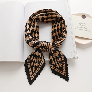 Detail of pleated scarf with black and brown geometric patterns on a white book