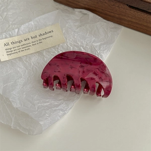 Detailed view of a dark burgundy marble pattern claw clip on white textured paper