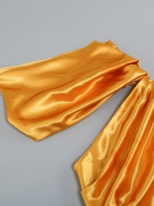 Close-up of golden yellow satin fabric showing silky sheen and elegant pleat textures