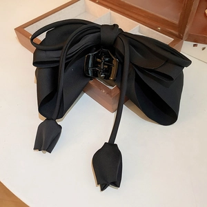 Détail de la pince à cheveux nœud noir avec pompon tulipe sur boîte à bijoux en bois