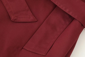 Vue macro d'un manteau rouge foncé montrant le tissu sergé et les détails des coutures