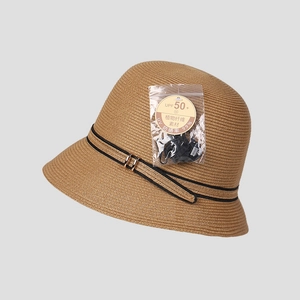 Detalle de sombrero de paja con cinta negra, hebilla dorada y textura tejida fina