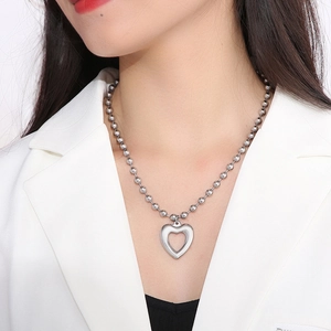 Polished silver beaded necklace with hollow heart pendant on female model wearing white blazer