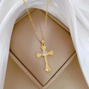 Macro shot of gold cross necklace with clear zircons in a beige jewelry box with white silk