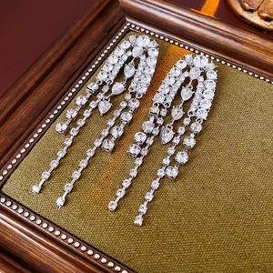 Detail of silver drop earrings with rhinestone tassels on a green velvet display