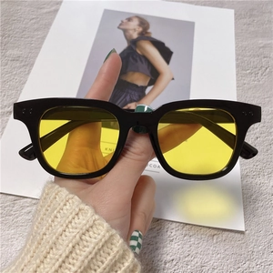 Retro black frame sunglasses with vibrant yellow lenses and silver rivet accents