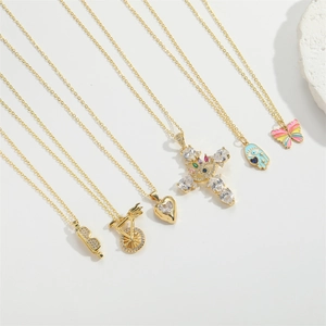 Détail de colliers dorés avec pendentifs en émail comme la croix, le papillon et l'oeil bleu