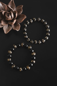 Detail of black obsidian beads with gold mantra carvings and a ceramic lotus flower