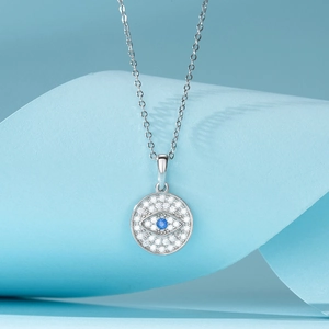 Silver geometric necklace with blue evil eye pendant and white zircon on light blue background