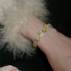 Macro detail of oval yellow zircon bracelet with silver claw setting and small crystals