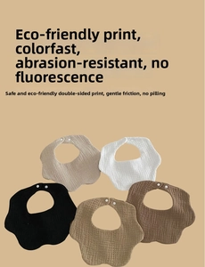 Close-up of five muslin cotton baby bibs with scalloped edges and white snap buttons