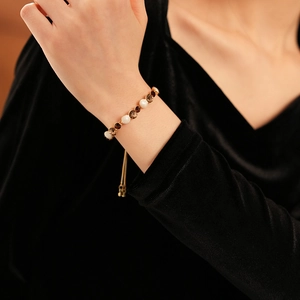 Détail d'un bracelet ajustable avec perles et pierres précieuses brunes dorées