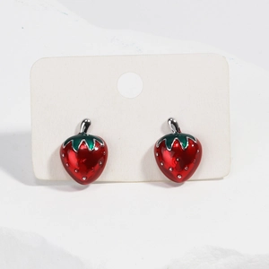 Détail des boucles d'oreilles fraises en émail rouge sur carte blanche et fond de pierre