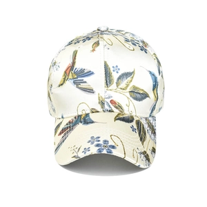 Detail of hummingbird and floral embroidery on a cream satin baseball cap surface