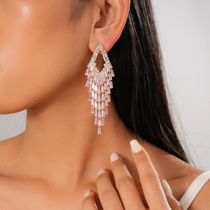 Close-up of geometric tassel earrings with pink rectangular stones on elegant model