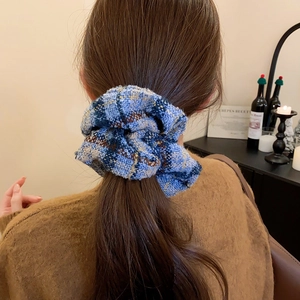 Modèle portant un chouchou en tricot à carreaux bleu et beige sur une queue de cheval
