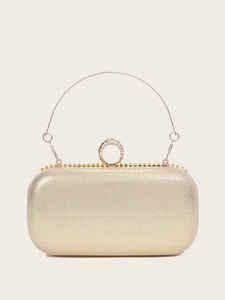 Detailed close-up of golden fringe evening bag with shimmering fabric and rhinestone clasp