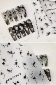 Macro detail of ink-style floral nail stickers with pearl accents on glossy finishes