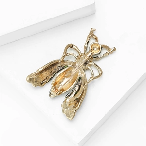 Detail shot of a golden insect-shaped brooch with rhinestones on a white pedestal