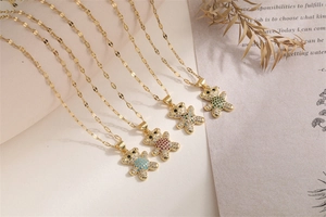 Close-up of golden bear pendants with colorful zircons arranged on a vintage paper background