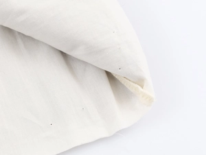Macro detail of natural cream knitted fabric showing fine texture and hemmed lockstitch