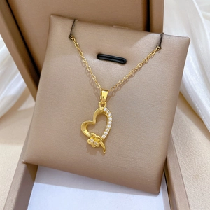 Detail of gold heart pendant with bow and rhinestones on luxury jewelry display stand