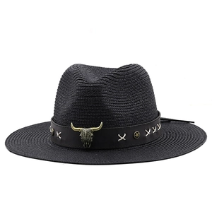 Close-up of black straw fedora hat with bronze bull skull metal piece and silver studs
