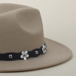 Detail of light camel wool fedora with black wavy band, floral accents, and silver rivets