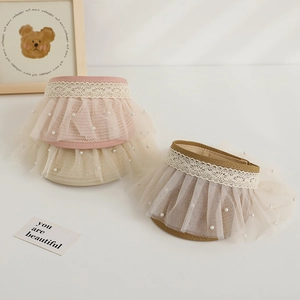 Detailed view of kids woven straw visor with delicate lace, mesh and pearl embellishments