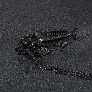 Detailed view of a vintage black metal fishbone pendant necklace on a dark background
