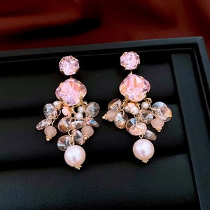 Macro detail of pink crystal earrings with tassel pearls and gold finish on black base