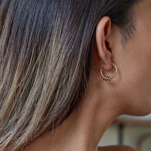 Detail of two-tone stainless steel C-shaped hoop earring with three metallic accent rings
