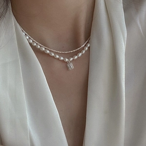 Detail of layered gold chain necklace with rectangular zircon and rice pearl accents