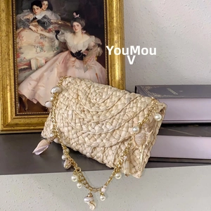 Detail of handmade woven straw bag with pearl, chain, and shell shoulder strap decoration