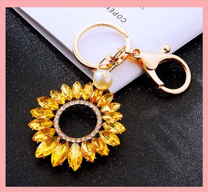 Macro detail of sunflower keychain with yellow rhinestones and elegant white pearl accent