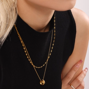 Gold layered necklace featuring triple interlocking rings with cubic zirconia on a model