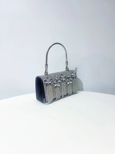 Detail of luxury velvet evening bag featuring crystal flower accents and fringe tassel