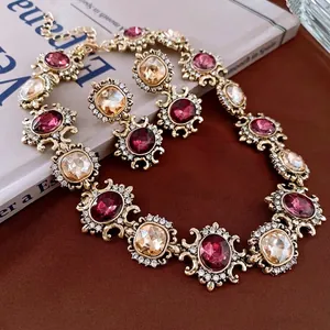 Vintage-style jewelry set with pink gemstones and crystals on a warm textured background