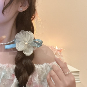 Detail of light blue silk bow hairpin with mesh flower and rhinestone on braided hair