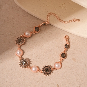 Bracelet tournesol en or rose avec perles roses et cristaux sur fond de pierre