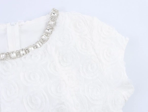 Détail du col d'une robe blanche avec tissu rose 3D et bordure en cristal de luxe