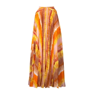 Detail of a pleated maxi skirt with vibrant orange and yellow tie-dye print pattern