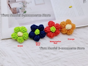 Detail of four handmade crochet milk cotton flowers in green, navy, red, and orange colors