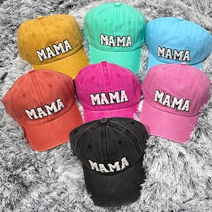 Detailed shot of six distressed cotton baseball caps with MAMA embroidery on plush background