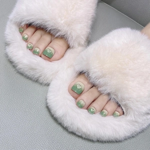 Close-up of green and milky white gradient press-on toenails with 3D heart decor