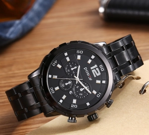 Detail of matte black men's chronograph watch on wooden desk with luxury finish
