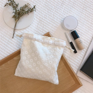 Detail of white cotton lace drawstring pouch with exquisite floral embroidery texture