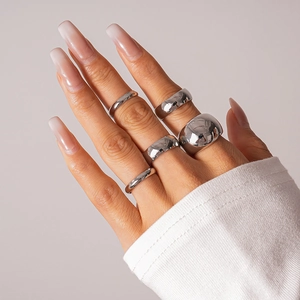 Polished silver geometric ring set worn on hand with neutral background and ribbed cuff